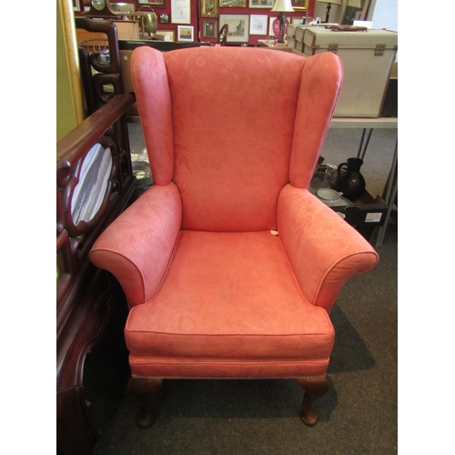 1195 - A pink silk upholstered wingback armchair on cabriole fore legs