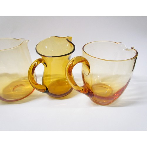 1314 - Four Amber glass jugs including Whitefriars.  Tallest 20cm