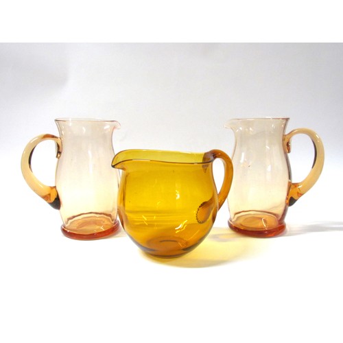 1317 - A pair of Amber glass jugs, 20cm high, together with a Whitefriars Gold/Amber jug, 15.5cm high (3)