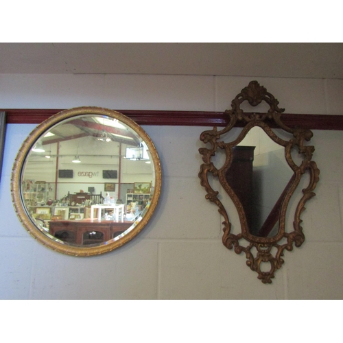 1014 - A rococo style gilt wall mirror with scrolled foliate design, 75cm long, together with a gilt circul... 