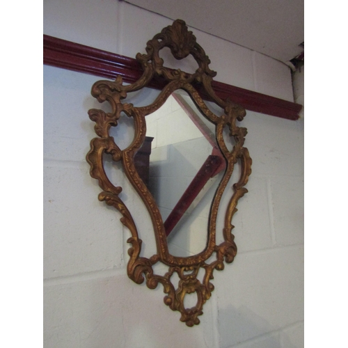 1014 - A rococo style gilt wall mirror with scrolled foliate design, 75cm long, together with a gilt circul... 