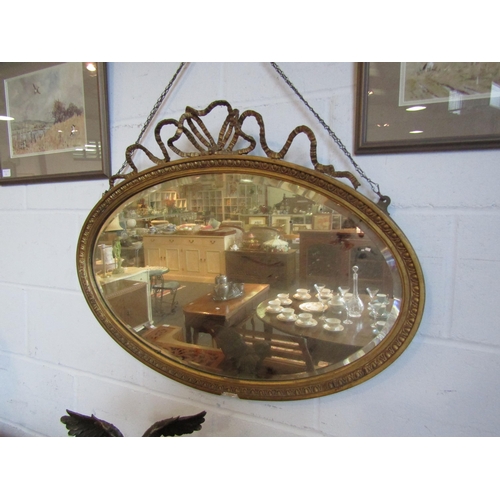 1018 - A 19th Century giltwood wall mirror of oval form, egg and dart frame, ribbon crest, some loss to fra... 