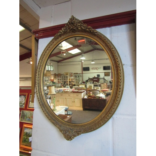 1020 - A gilt gesso wall mirror of oval form, floral and foliate relief, 57.5cm diameter