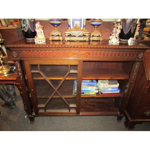 1114 - An early 20th Century mahogany bookcase with two astragal glazed sliding doors, blind fretwork friez... 