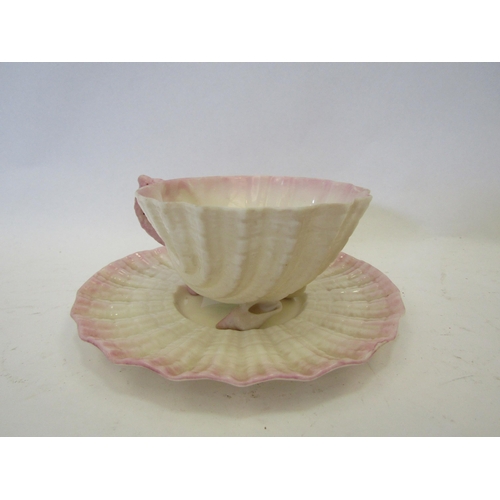 1402 - A Belleek shell form pattern cup and saucer, blush pink with shell form feet