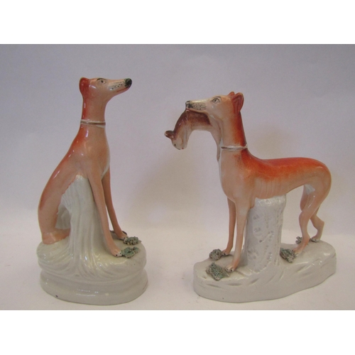 1408 - A Victorian Staffordshire pottery figure of a greyhound, standing with a hare in its mouth and a sim... 