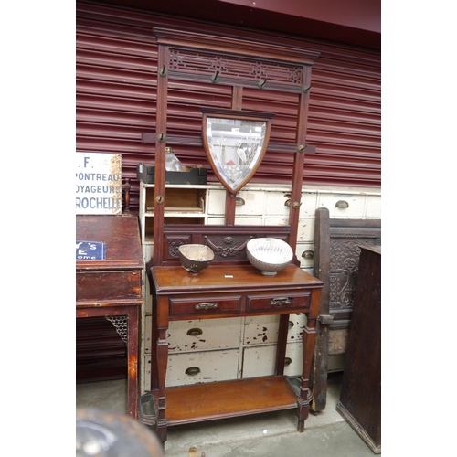 2083 - An early 20th Century hall stand, shield form bevelled mirror, on faceted front supports