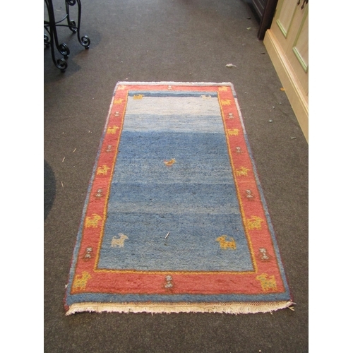 1172 - A blue ground rug with red border and animal detailing, 130cm x 75cm