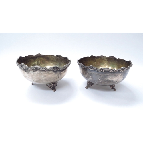 6444 - Two silver bowls raised on three feet with scroll decorated rim, both marked 800, 6cm tall, 11cm dia... 