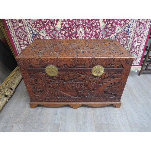 6023 - A Chinese carved camphor chest with allover decoration depicting figures crossing bridges trees and ... 