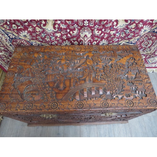 6023 - A Chinese carved camphor chest with allover decoration depicting figures crossing bridges trees and ... 