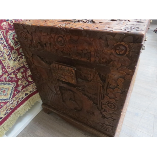 6023 - A Chinese carved camphor chest with allover decoration depicting figures crossing bridges trees and ... 