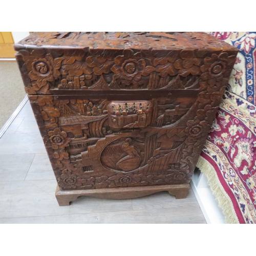 6023 - A Chinese carved camphor chest with allover decoration depicting figures crossing bridges trees and ... 