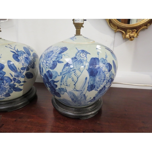 6064 - A pair of blue and white ginger jars as table lamps with blossom, bird and leaf decoration, circular... 