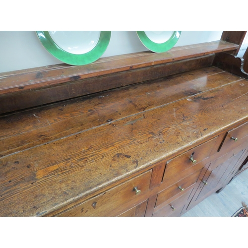 6091 - A Georgian country house oak dresser, the open plate rack top over a six drawer and two door cupboar... 