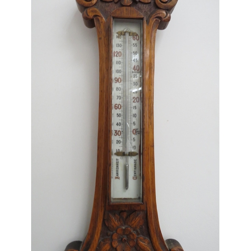 6097 - An early 20th Century carved oak cased barometer with thermometer dial