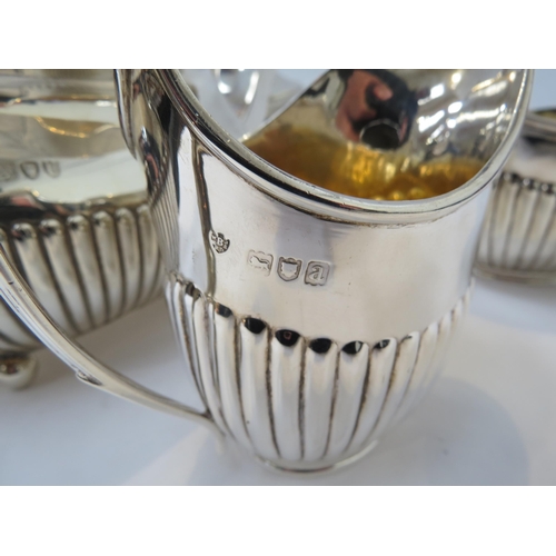 6386 - A silver matched four piece tea set with melon fluting, inscription to water jug, 1488g approx