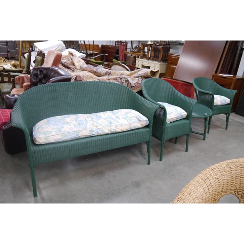 2442 - A Lloyd Loom glass topped two tier coffee table, two single chairs and a sofa, all matching green