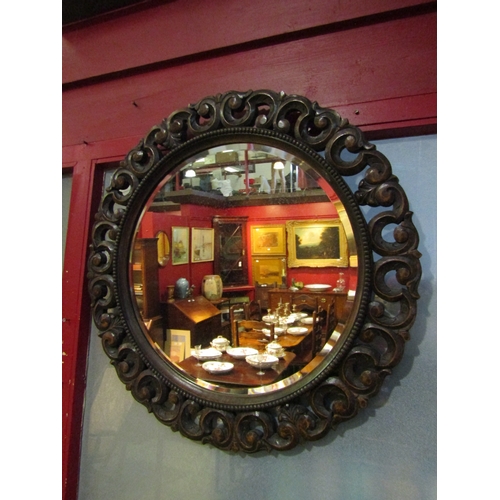 4019 - A circular wall mirror in a carved oak frame with bevelled edge and beaded detail, 69cm diameter