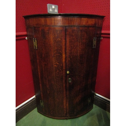 4033 - A North Country George III oak and mahogany crossbanded two door bow front corner cupboard with bras... 