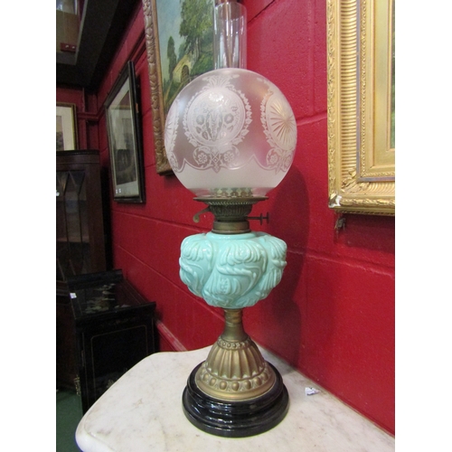 4145 - A Victorian oil lamp, the engraved frosted glass globular shade over a turquoise foliate relief rese... 