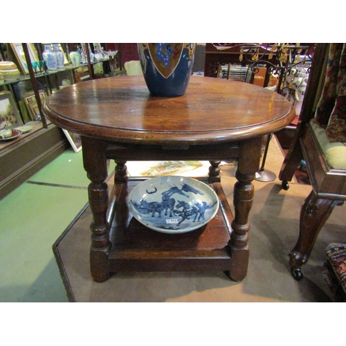 4222 - An 18th Century style country oak coffee table, circular top, turned supports over an under-tier, 48... 