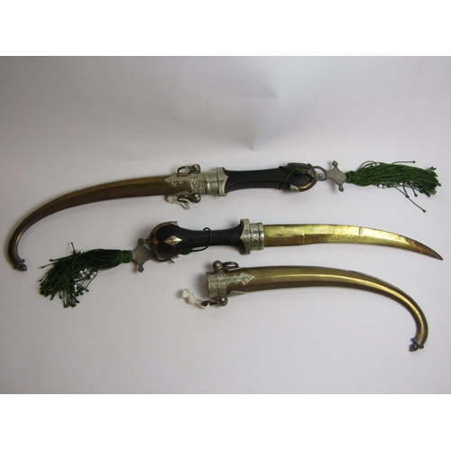 4343 - A pair of Moroccan/North African decorative daggers, both with curved brass blades, engraved mounts