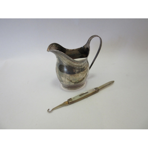 1306 - A George III silver jug, London 1800, maker's marks rubbed, and a fruit knife with mother-of-pearl h... 