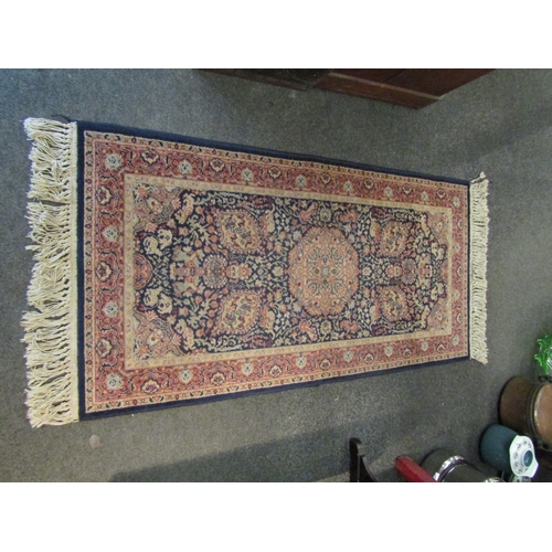 1018 - An Eastern wool blue ground floral design rug with tasselled ends, 135cm x 68cm