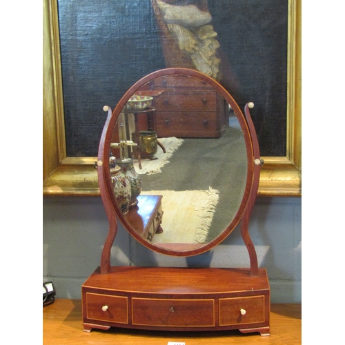 1063 - An oval dressing table mirror with three drawer bow front base