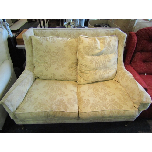 1137 - A modern two seater sofa, gold coloured upholstery with swag design on castors to fore legs