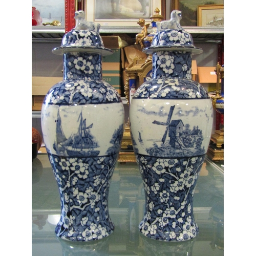 1167 - A pair of Delft Blue and white vases with floral design and central panel of windmill and river scen... 