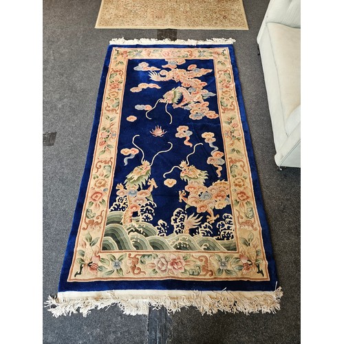 1017 - A blue ground Chinese rug, dragons chasing the flaming pearl, floral decoration and border, tasselle... 