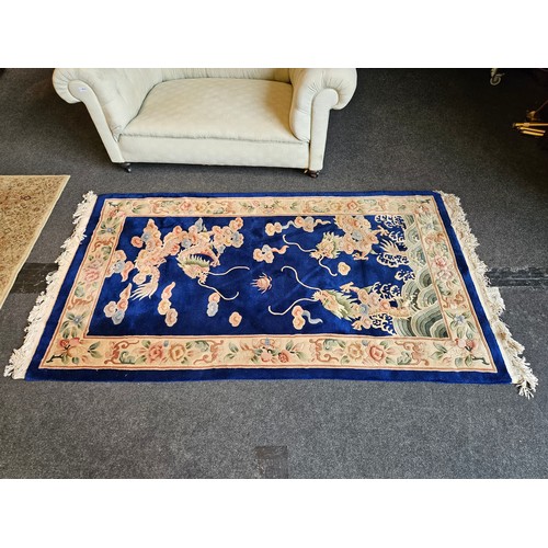 1017 - A blue ground Chinese rug, dragons chasing the flaming pearl, floral decoration and border, tasselle... 