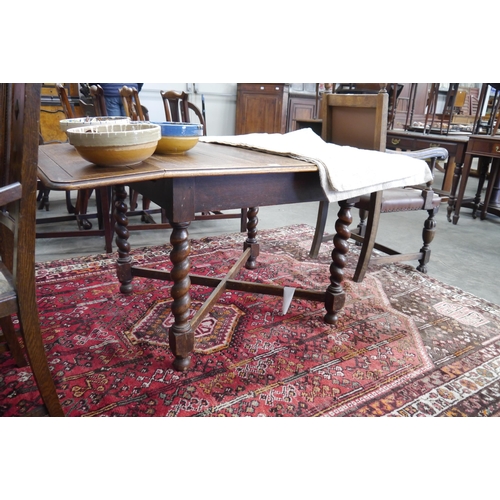 2198 - A 1930's oak drop-leaf table of barley-twist supports and cross stretching