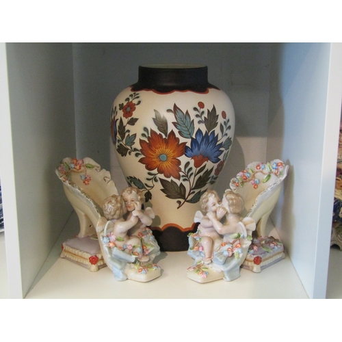 1363 - A pair of Continental porcelain shoes surmounted by cherubs and cushion to heel and a 