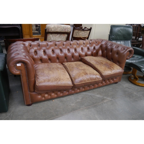 2359 - A worn brown leather three seater button back sofa