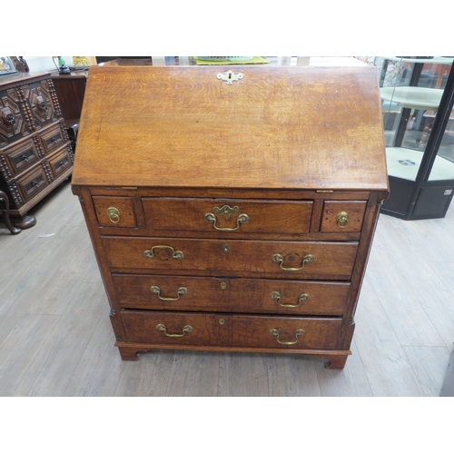 4117 - A George III oak bureau, the fitted interior enclosed by a fall-front, over three small and three lo... 