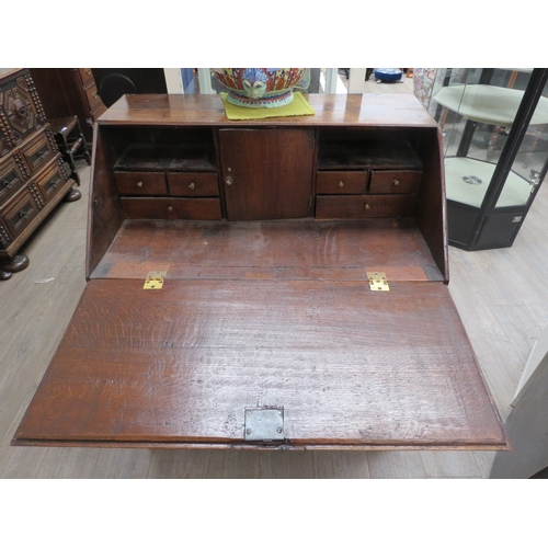 4117 - A George III oak bureau, the fitted interior enclosed by a fall-front, over three small and three lo... 