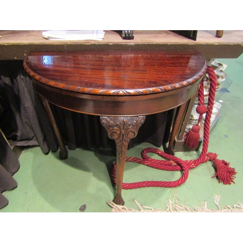 4005 - A Georgian mahogany demi-lune games table, the hinged fold-over top on carved cabriole legs with hai... 