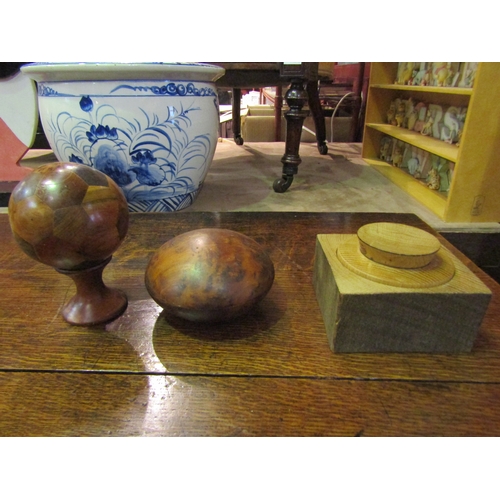 4024 - A burr wood lidded box, a wooden ball on stand with multiple wood types, together with another woode... 