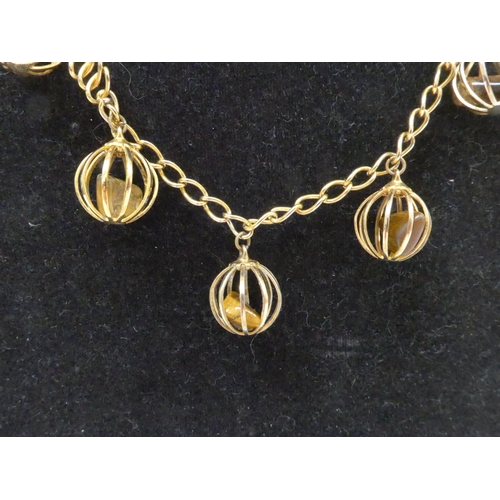 7335 - A 1970's ferris wheel type necklace in gold tone with seven cages containing Tigers eye stones