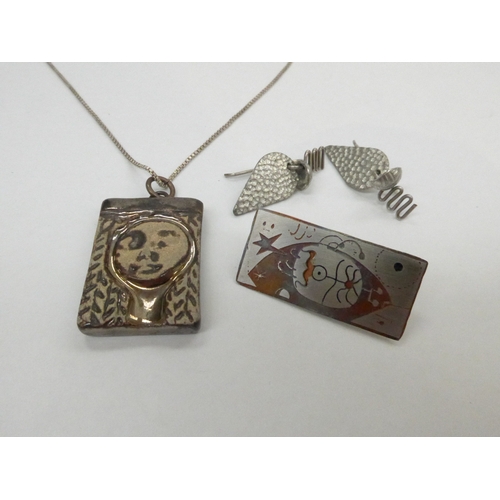 7340 - An 'Avante-garde' stylised pottery face pendant on silver chain, together with a futuristic mixed me... 