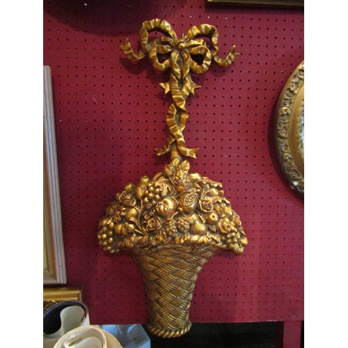 1063 - A gilt wall hanging decoration as ribbons and a fruit basket, 65cm tall