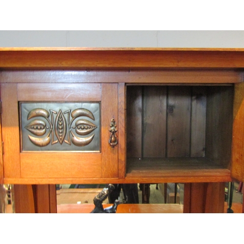 1080 - An Arts & Crafts oak sideboard with raised mirrored back, four cupboard doors with copper panels ove... 