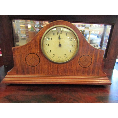 1142 - A mahogany inlaid 10-day mantel clock on brass ball feet