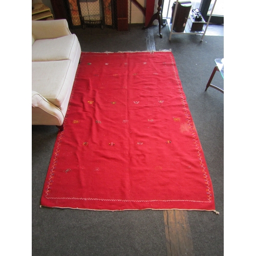 1028 - A Moroccan red ground wool rug, stained, 244cm x 155cm