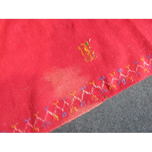 1028 - A Moroccan red ground wool rug, stained, 244cm x 155cm