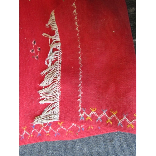 1028 - A Moroccan red ground wool rug, stained, 244cm x 155cm