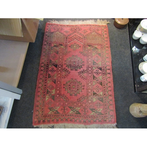 1462 - An Eastern red ground geometric design rug with tasselled ends, 112cm x 76cm